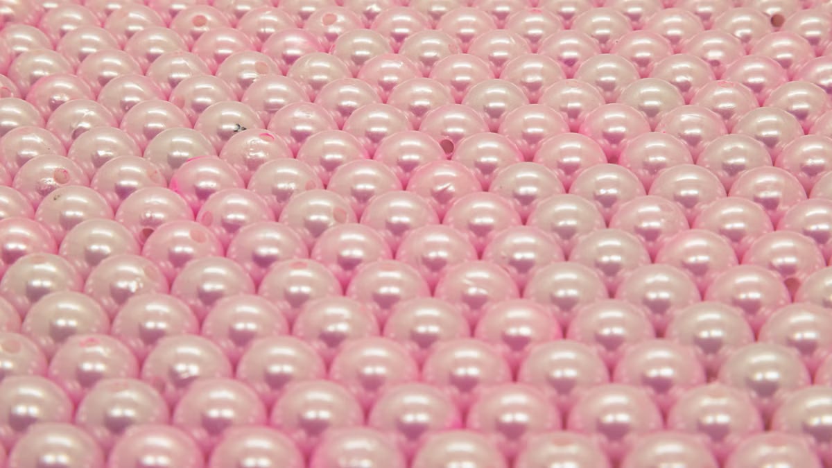 A detailed still life of pink pearls arranged in a structured pattern. Ideal for texture or jewelry-themed designs.